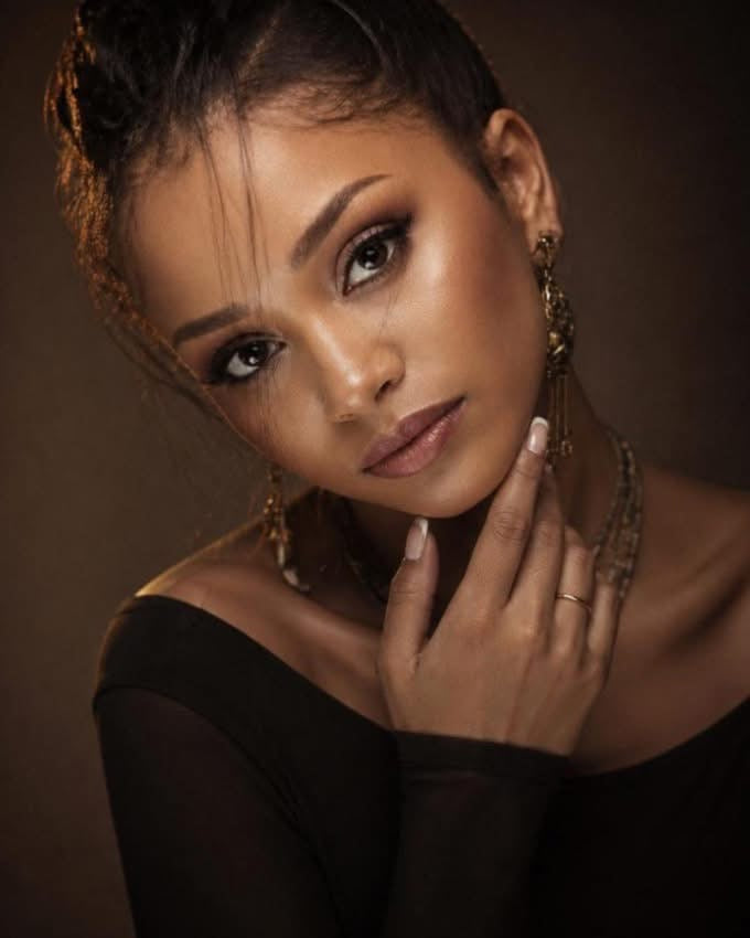 Woman with stylish hair and jewelry against a brown background